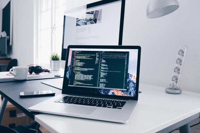 An open laptop, sitting on a desk, on which HTML and CSS are being written in Sublime Text.